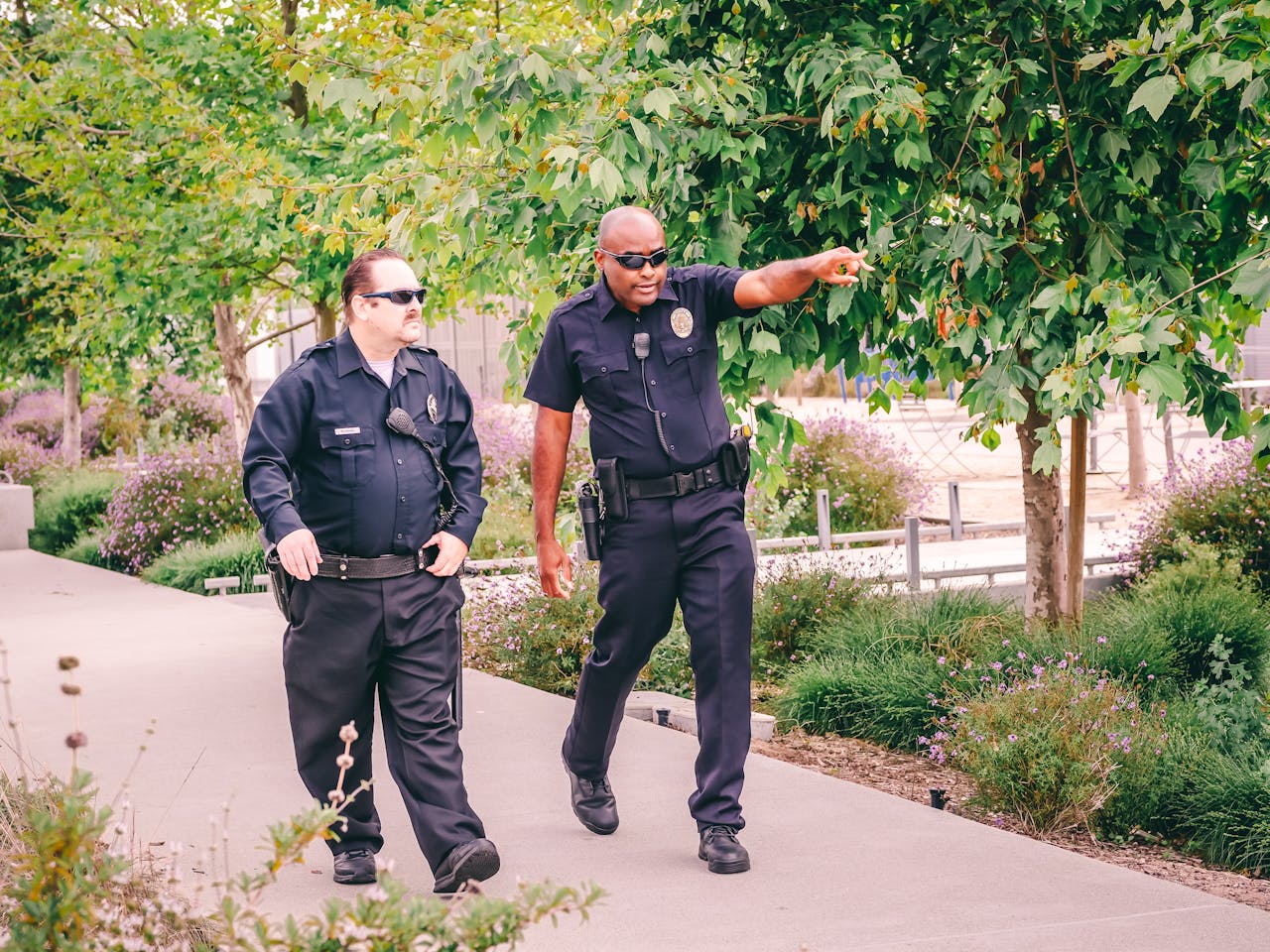 Two police officers walking along a park path in uniform, ensuring public safety.